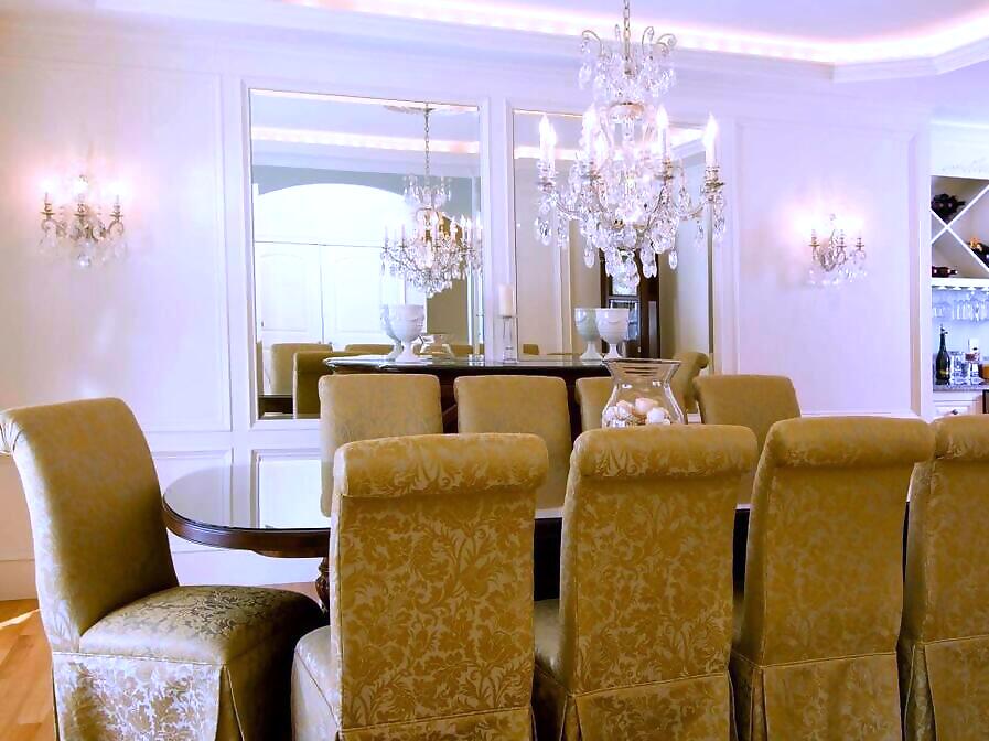 Dining room with a crystal chandelier, matching wall sconces and cove lighting
